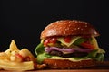 Homemade burger with grilled beef, cheese, onion, tomato, and green salad, sauce, with pickles and French fries Royalty Free Stock Photo