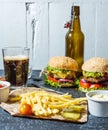 Homemade burgers with beef and fried potatoes and glass of cold dark beer on stone table Royalty Free Stock Photo