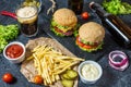 Homemade burgers with beef and fried potatoes and glass of cold dark beer on stone table Royalty Free Stock Photo