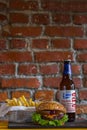 Homemade burgers with beef pear and cherry and french fried potatoes and bottle of cold beer on wooden table on a brick background Royalty Free Stock Photo