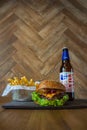 Homemade burgers with beef pear and cherry and french fried potatoes and bottle of cold beer on wooden table on a wood background Royalty Free Stock Photo