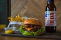 Homemade burgers with beef pear and cherry and french fried potatoes and bottle of cold beer on wooden table on a wood background