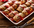 Homemade cabbage rolls stuffed with groats and mushrooms with tomato sauce in a baking dish on a wooden table Royalty Free Stock Photo