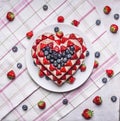 Homemade cake In the form of heart with blueberries and strawberries On a white plate a background of a striped pink napkins w