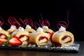 Homemade cake roll with strawberry cream a on a black slate. Royalty Free Stock Photo