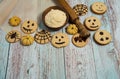 Cornmeal, rolling pin, baking paper, cookies with spiders, bats, pumpkins, scary smiles, cobwebs on a light blue wooden background