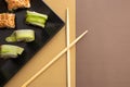 Homemade california and cucumber sushi rolls with sesame seeds on a black square plate on a brown beige background with wooden Royalty Free Stock Photo