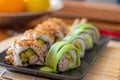 Homemade california and cucumber sushi rolls with surimi fake crab meat, avocado and fried sesame seeds. Served in two rows on a