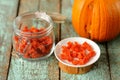 Homemade candied pumpkin pieces in glass jar and white plate wit