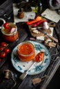 Homemade canned hot tomato sauce adjika in glass jar standing on vintage plate