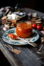 Homemade canned hot tomato sauce adjika in glass jar standing on vintage plate