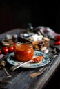 Homemade canned hot tomato sauce adjika in glass jar standing on vintage plate