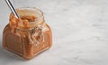 Homemade caramel sauce in a glass jar on a light table. Close-up, copy space. Sweet dessert Royalty Free Stock Photo