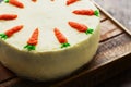 Homemade carrot cake with orange carrots on wooden background