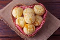 Homemade cheese bread, traditional Brazilian snack, in a heart-shaped basket on a rustic kitchen table Royalty Free Stock Photo