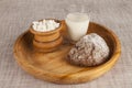 Homemade cheese, a glass of milk, brown bread on a wooden tray.