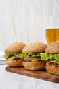 Homemade cheeseburgers and glass of beer on a white wooden surface, side view. Close-up