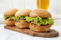 Homemade cheeseburgers on rustic wooden board and glass of cold beer, side view. Closeup. Selective focus