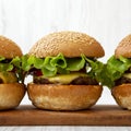 Homemade cheeseburgers on rustic wooden board, side view. Closeup