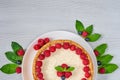 Homemade cheesecake with fresh berries on the white plate decorated with raspberries and blueberries, mint on the gray table Royalty Free Stock Photo