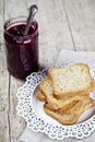 Homemade cherry jam in glassjar and fresh toasted cereal bread slices stack on white  plate closeup on linen napkin on rustic Royalty Free Stock Photo