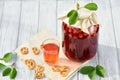 Homemade cherry preserved canned compote in glass with cookies on white wooden table in garden