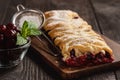 Homemade cherry puff pastry braid, on blue wooden background.