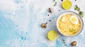 Homemade chicken bouillon or broth with noodle and egg served with thyme and lime on blue stone background. Top view. Copy space