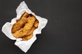 Homemade chicken fingers in paper box on a black background, top view. Flat lay, overhead, from above. Copy space Royalty Free Stock Photo