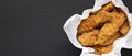 Homemade chicken fingers in paper box on a black background, top view. Flat lay, overhead, from above. Space for text Royalty Free Stock Photo