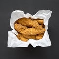 Homemade chicken fingers in paper box on a black surface, top view. Flat lay, overhead, from above. Close-up Royalty Free Stock Photo