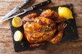 Homemade chicken rotisserie with thyme, lemon closeup on a slate board. Horizontal top view