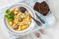 Homemade chicken soup with noodles and vegetables with celery greens on a cotton napkin,with a spoon and fork. Pieces of rye bread