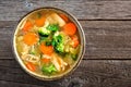 Homemade chicken vegetable soup, close up view over wood