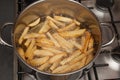 Homemade chips or fries deep frying in a deep pan