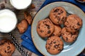 Homemade chocolate cookies in a plate with milk on a wood background.