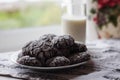 Homemade chocolate cookies with powdered sugar on the plate and glass of milk near the window. Tasty breakfast in the morning Royalty Free Stock Photo