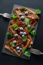 Homemade chocolate crepes served with blueberries, sauce and mint leaves on slate plate. Selective focus. Top view. Copy space Royalty Free Stock Photo