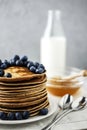 Homemade Chocolate Pancake with blueberries on a concrete gray background with milk and honey. Food photography of a