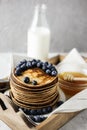 Homemade Chocolate Pancake with blueberries in a wooden tray on the linen napkin with milk and honey. Food photography