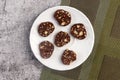 Homemade chocolate sausage. Dessert made of biscuits, chocolate and nuts is sliced on a white round plate on a dark background.