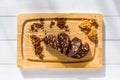 Homemade chocolate sausage sliced on a wooden board at sunny kitchen. Dessert made of biscuits, chocolate and nuts