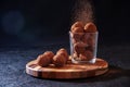 Homemade Chocolate Truffles in Glass with Sifting Cocoa on Wooden Board on Dark Stone Table and Background. Copy Space