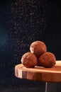 Homemade Chocolate Truffles with Sifting Cocoa on Wooden Board on Dark Background. Copy Space For Your Text