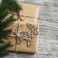 Homemade Christmas gift in kraft paper, wooden Christmas deer ornament, Christmas tree branches on rustic light wooden surface. Fr Royalty Free Stock Photo