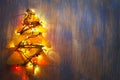 Homemade Christmas tree with lights illuminated on a wooden back