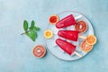 Homemade citrus ice cream or popsicles decorated mint leaves and orange slices on blue table from above. Frozen fruit juice. Royalty Free Stock Photo