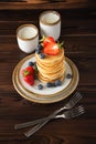 Homemade classic american pancakes with fresh blueberries, strawberries and two caps of milk Royalty Free Stock Photo