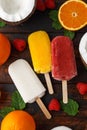 Homemade Coconut, Orange, raspberry popsicles, ice lolly, on wooden table. Summer food.