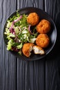 Homemade codfish cake and fresh salad closeup on a plate. Vertical top view Royalty Free Stock Photo